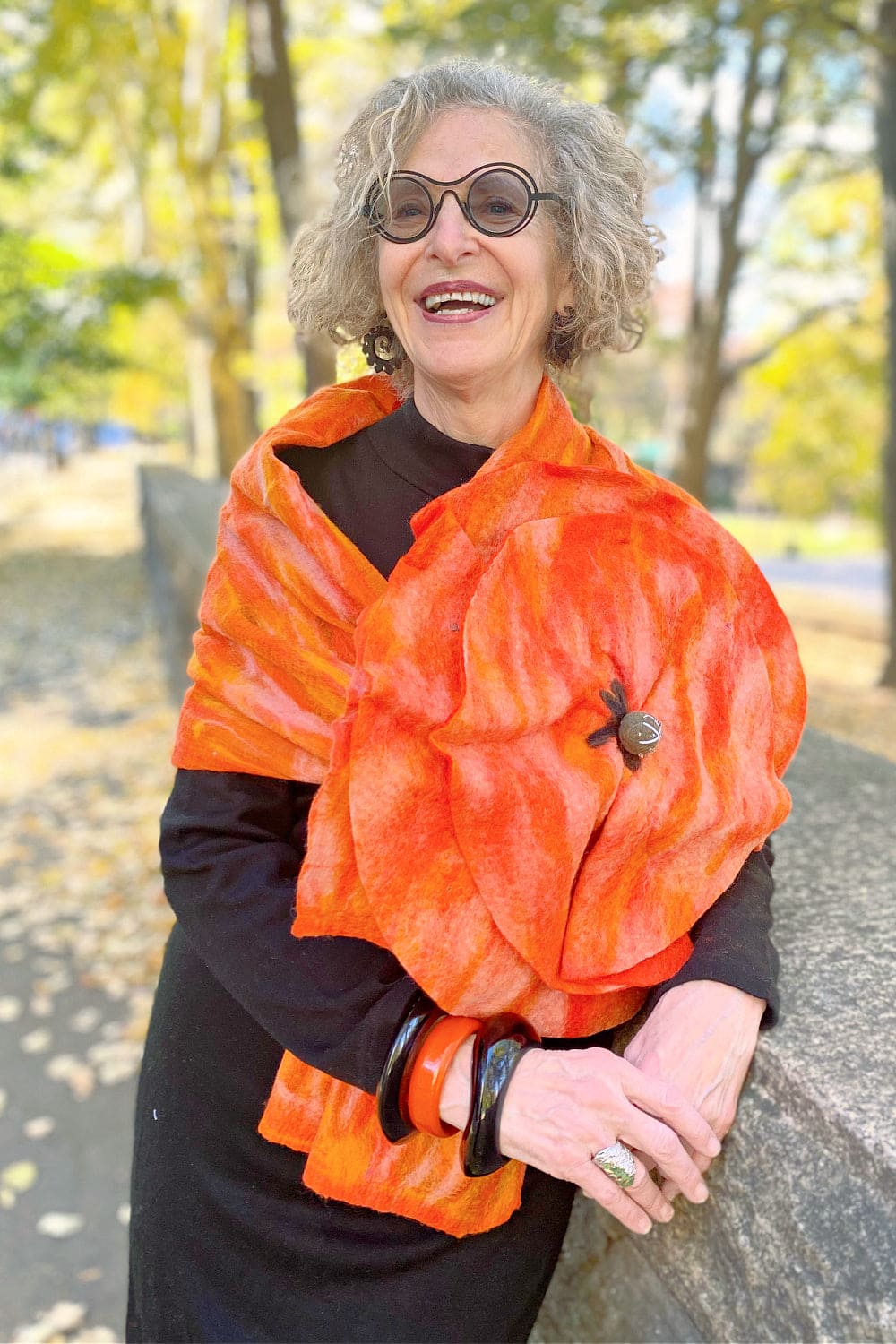 Orange Felted scarf wth dramatic flower worn on a stylish older woman.