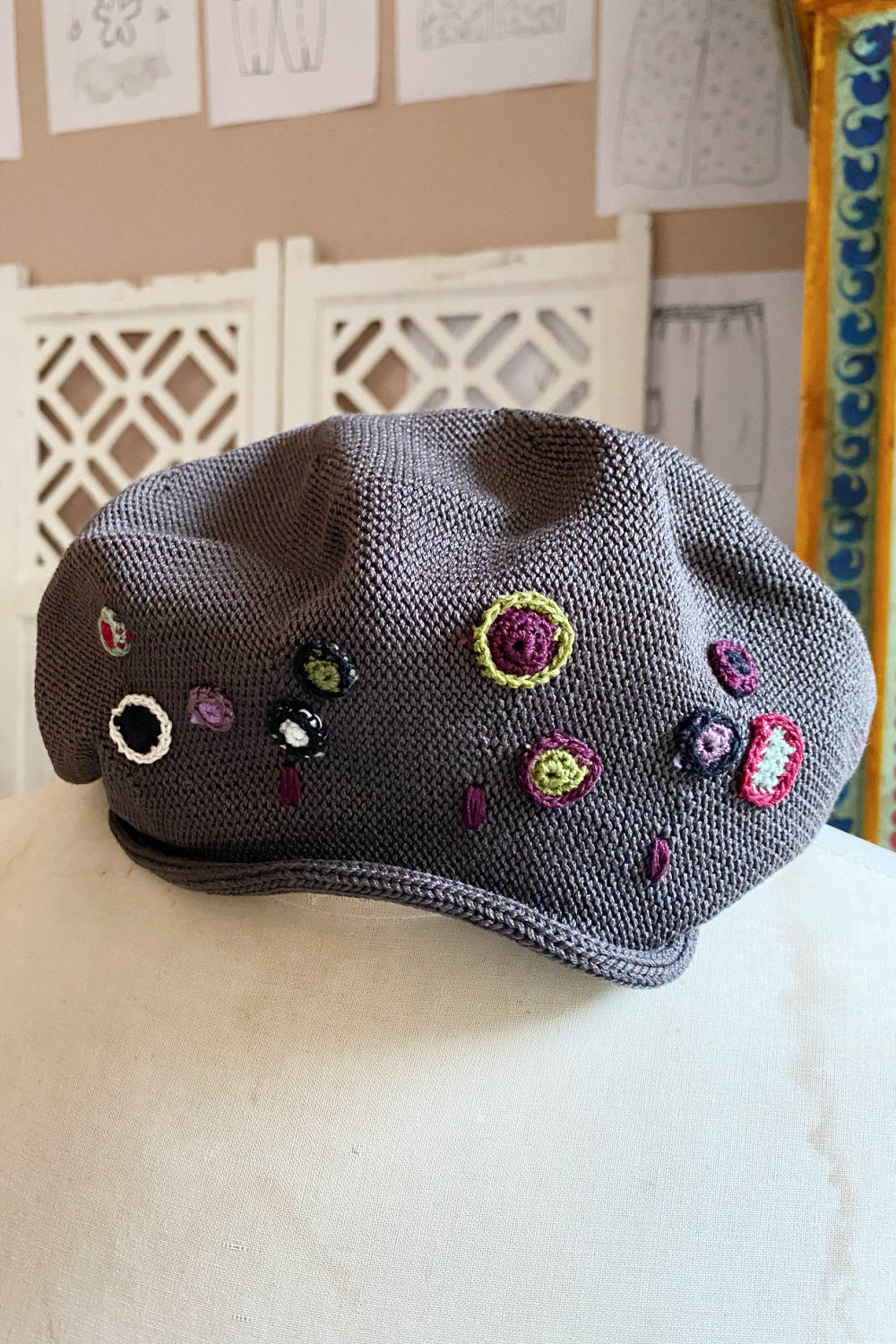 Grey knit tam with croquet floral decoration.