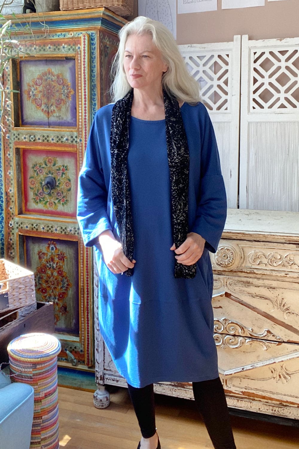 Silver haired woman wearing loose fit blue dress.