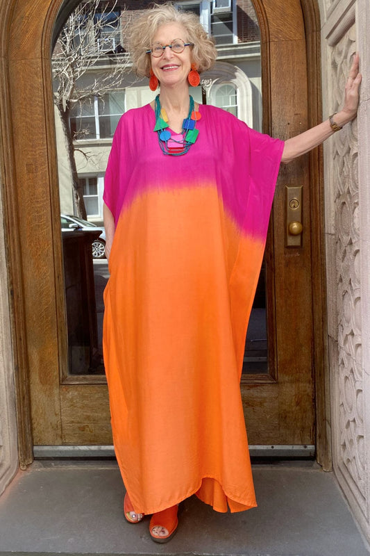 Pink and Orange Ambred women's caftan with funky colorful statement necklace an large red earrings.