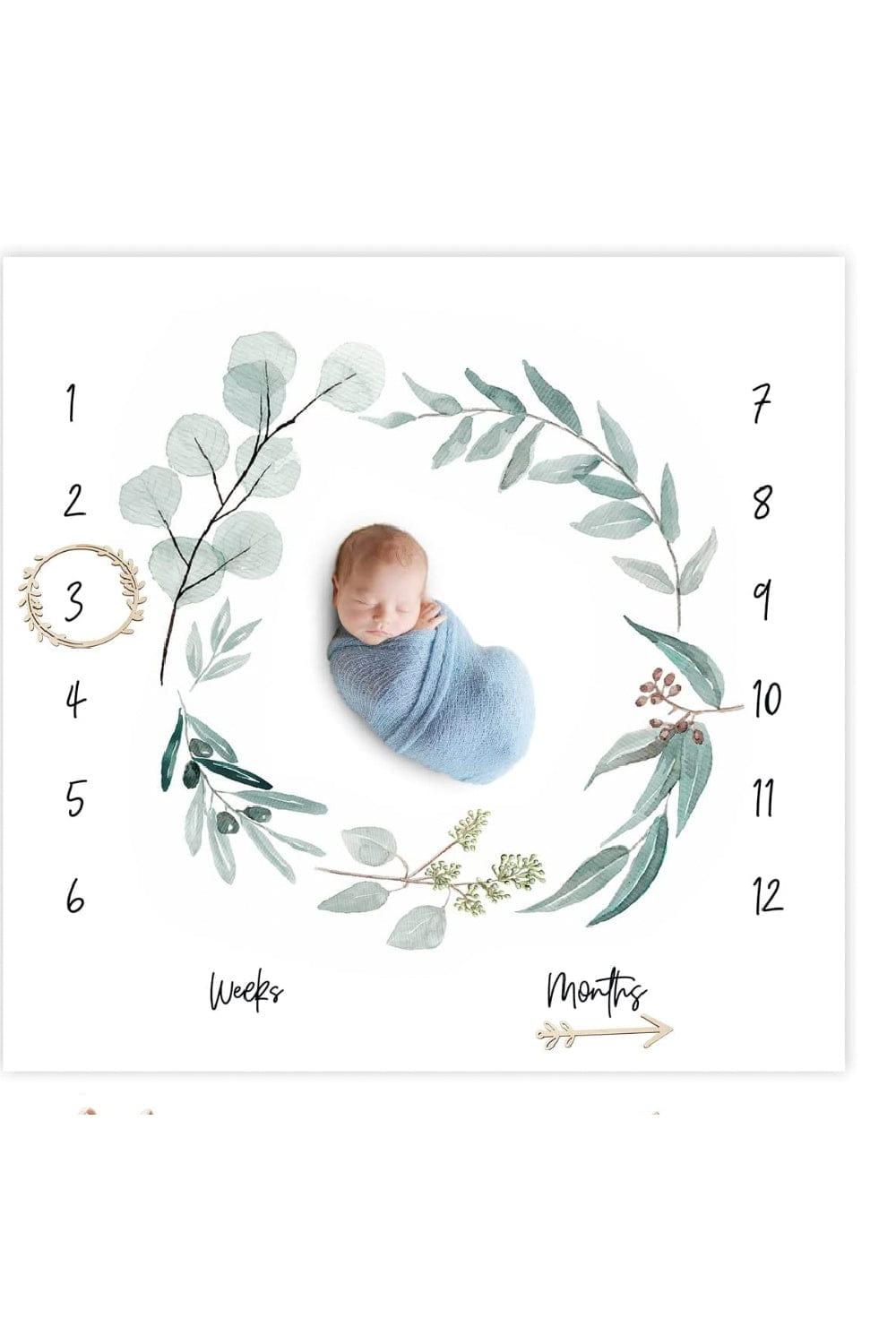 Newborn baby sleeping on a milestone blacket designed with a eucalyptus wreath print.