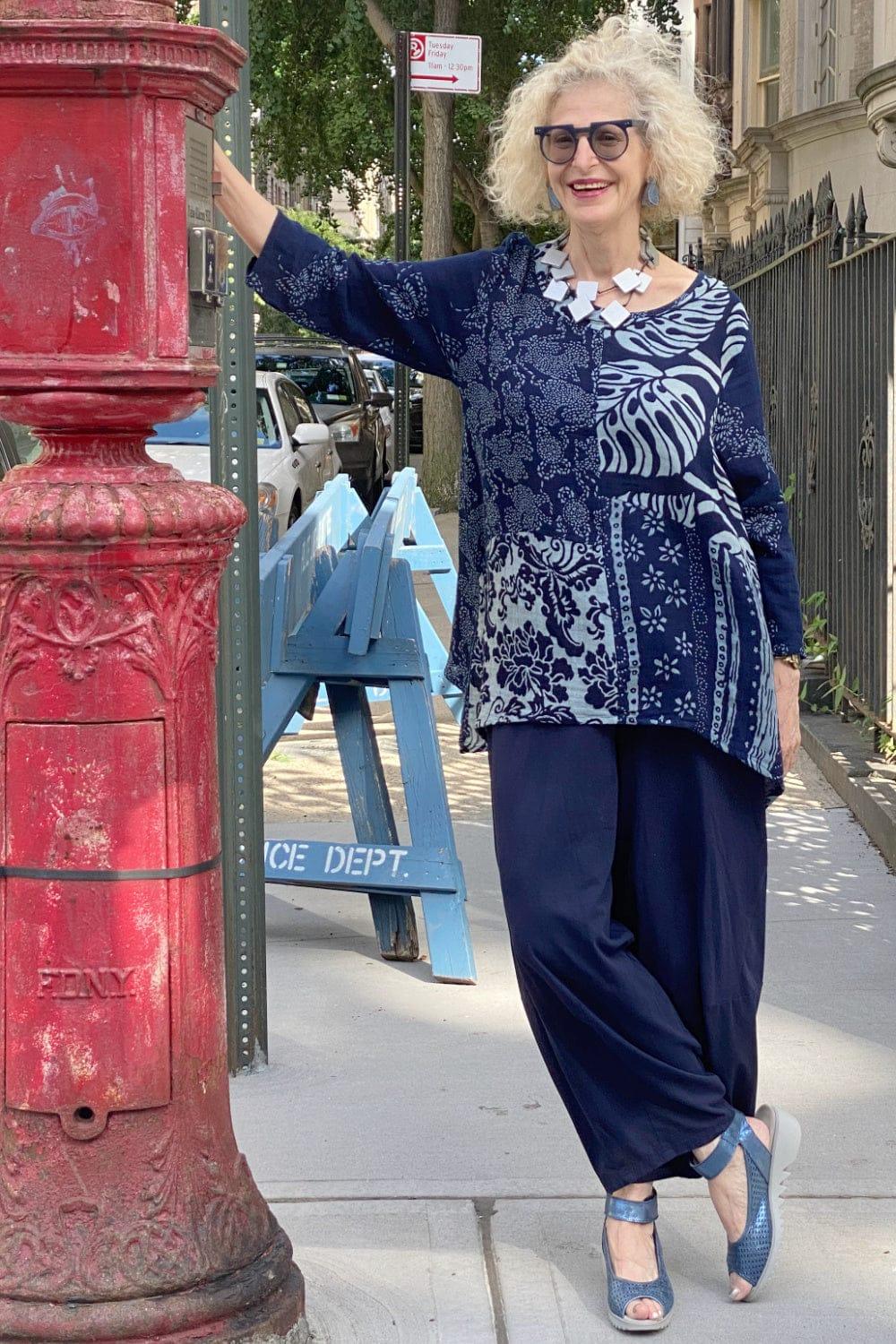 Pretty older woman modeling on street. She is wearing an indito multi patterned long sleeve tunic with wooden squares necklace.