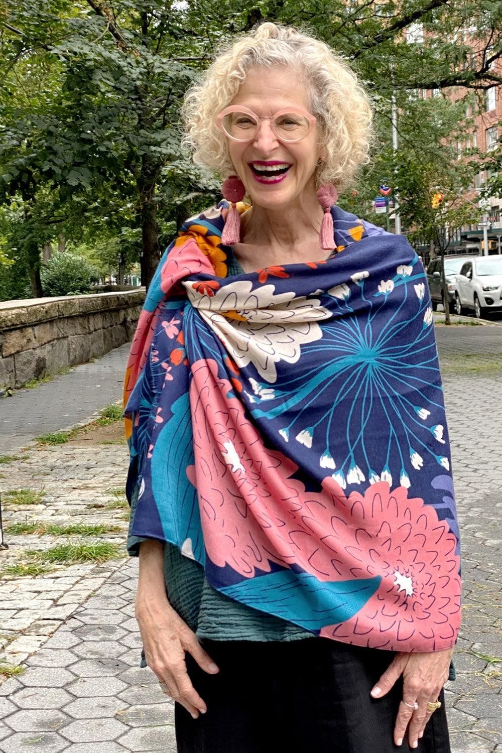 Pretty blues and pinks floral print scarf is draped around the shoulders of a laughting older woman.