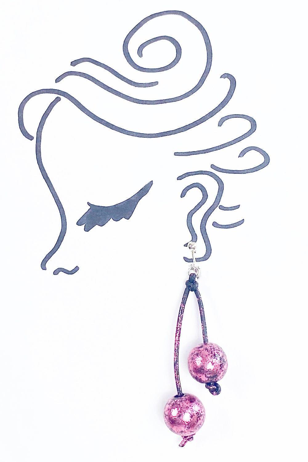 Women's funky earring made of two pink gilden balls hanging from leatherette cord 
